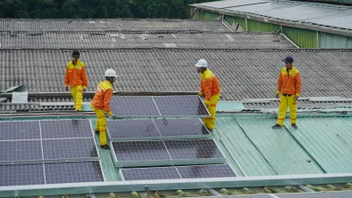 Workers fixing solar panels onto a roof.