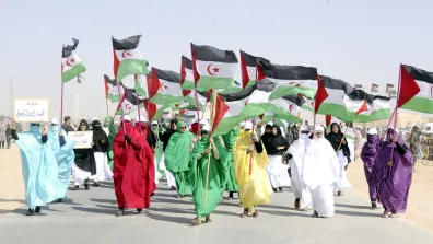 6 people hold Western Saharan flags at the front of a group of people