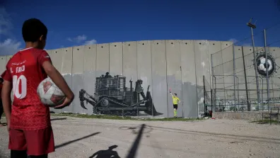 Boy holds football and looks at graffiti 