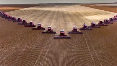 A field with lots of tractors lined up on it. The sky looks grey with dark clouds.