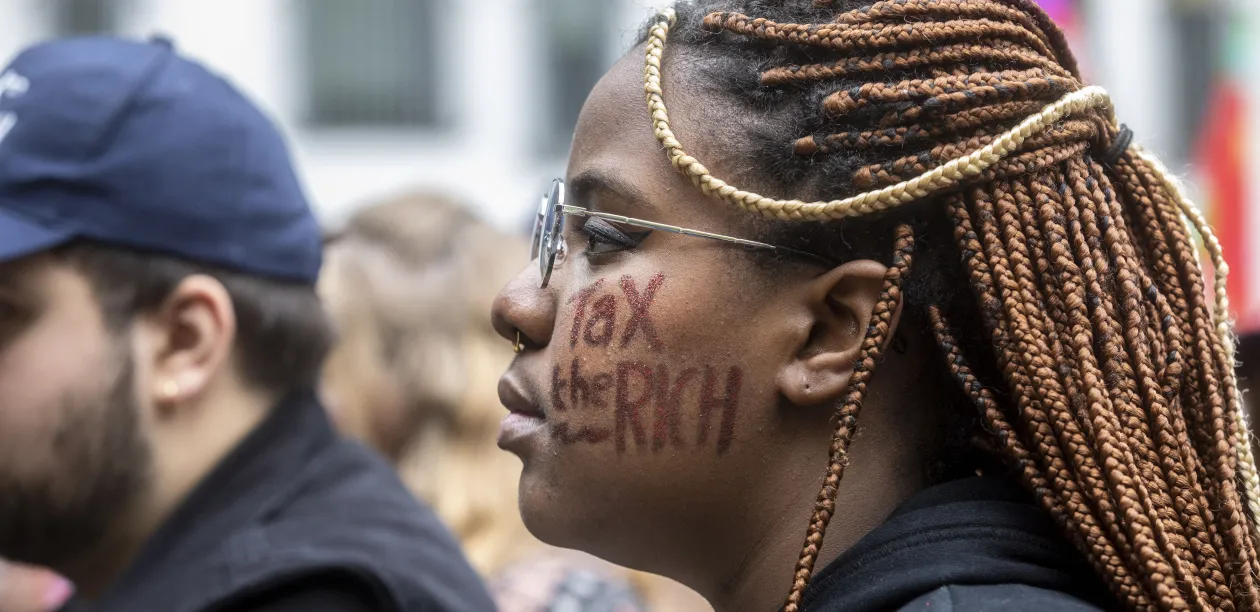 Profile of a woman with 'Tax the Rich' written on her face
